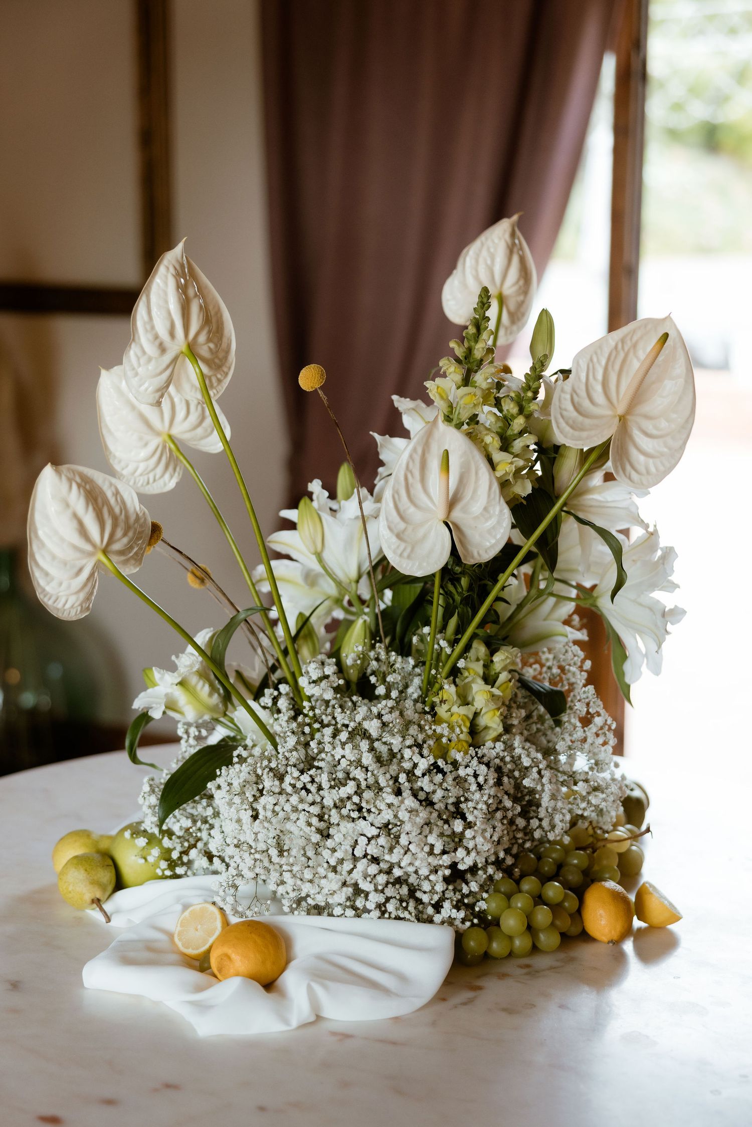 White anthurium flowers and baby's breath create an elegant floral arrangement on a light surface.