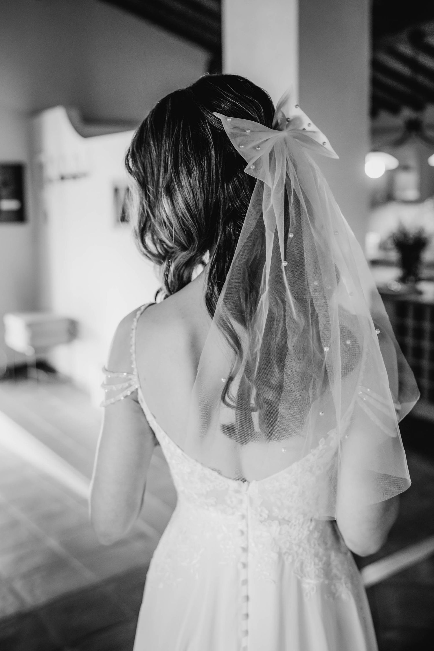 Back view of a bride in a delicate wedding dress with a sheer veil.