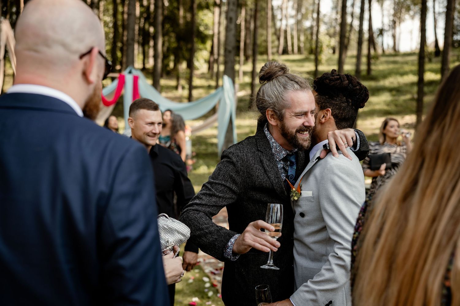 Wedding guests socializing and celebrating with drinks at an outdoor reception.