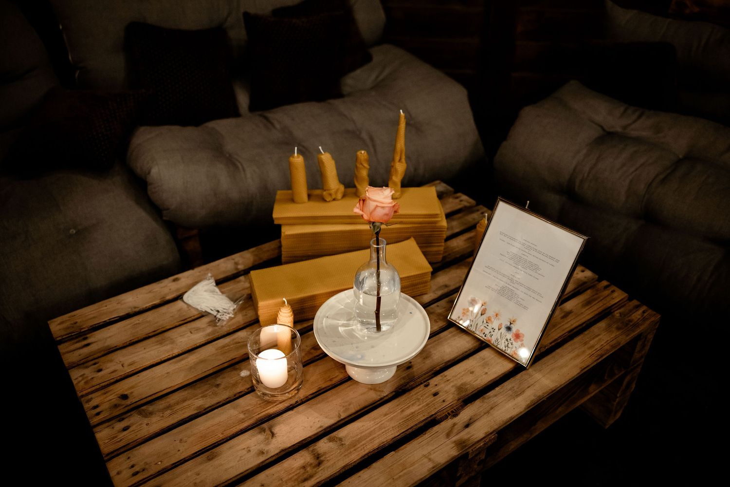 Rustic wooden pallet table with lit candles, amber colored candle stand, and small table decor in a dimly lit space.
