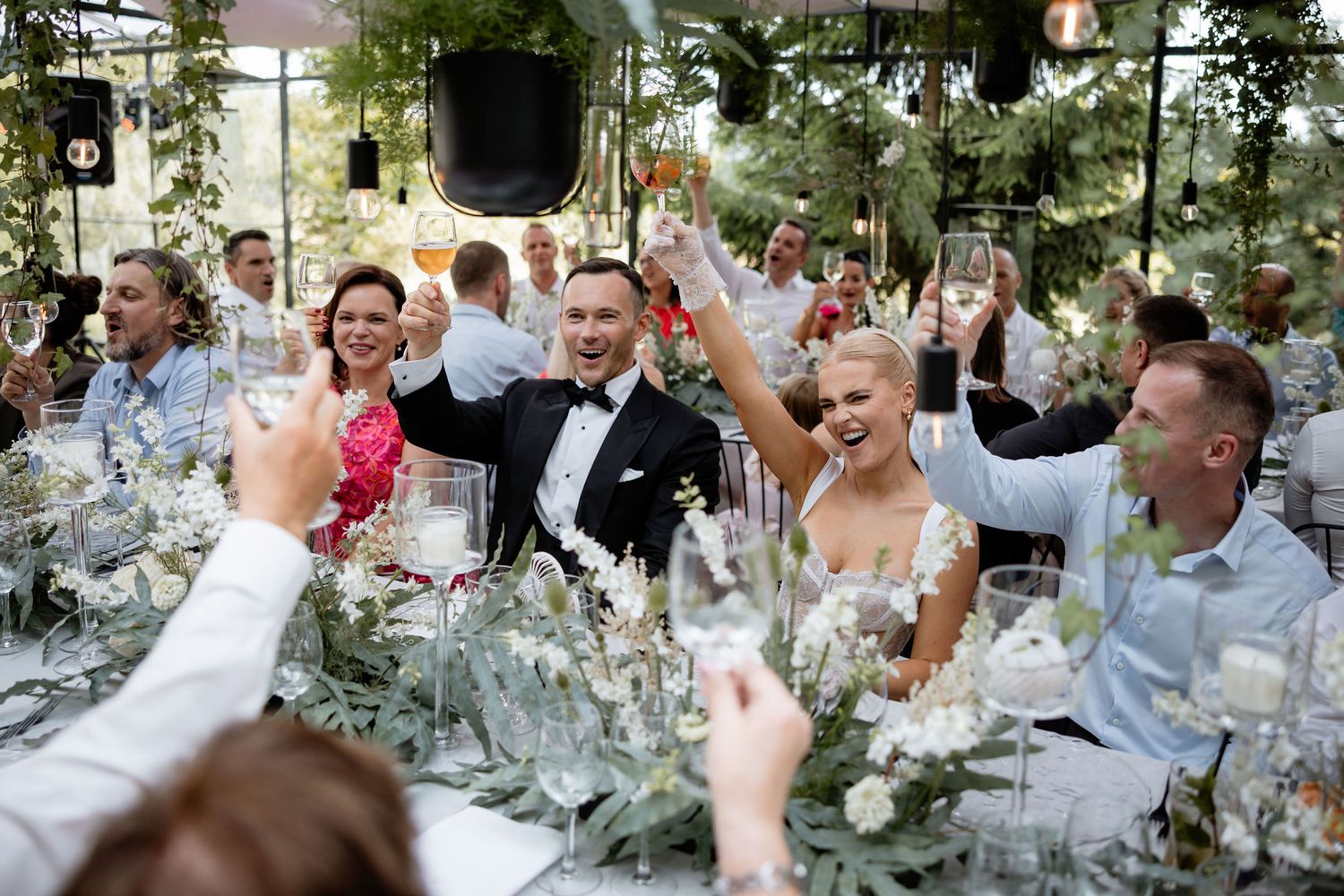 Celebratory moment at wedding reception with guests raising glasses for a toast.