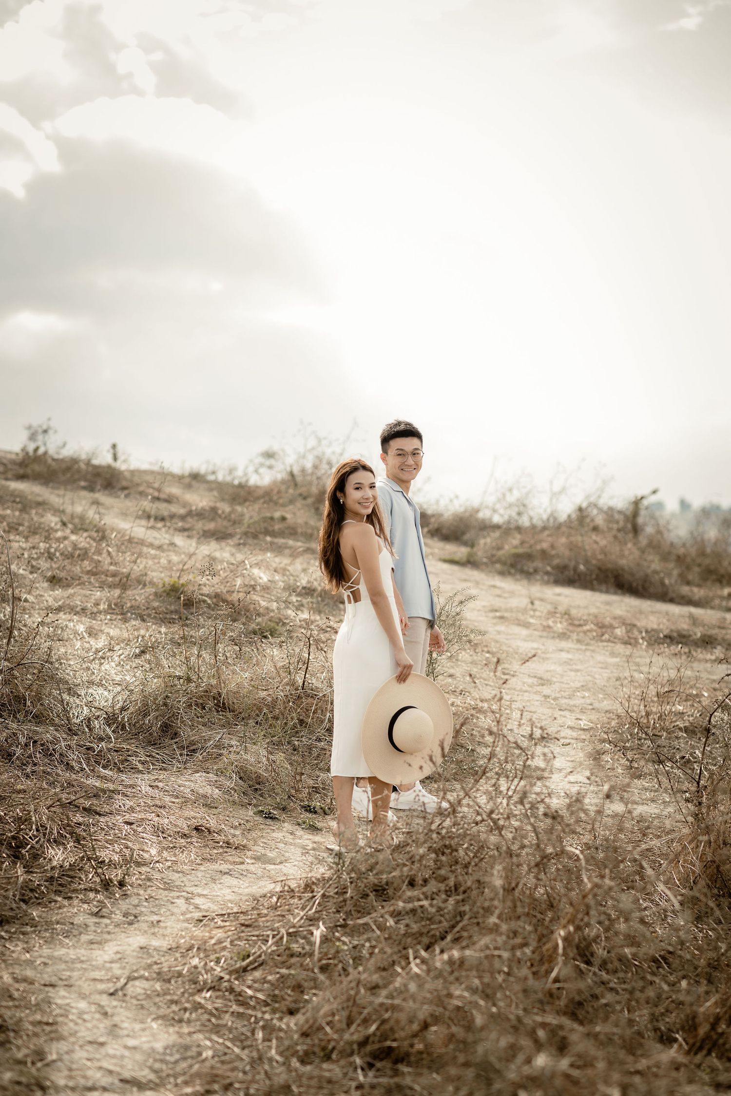Couple posing on hillside path during golden hour photoshoot.