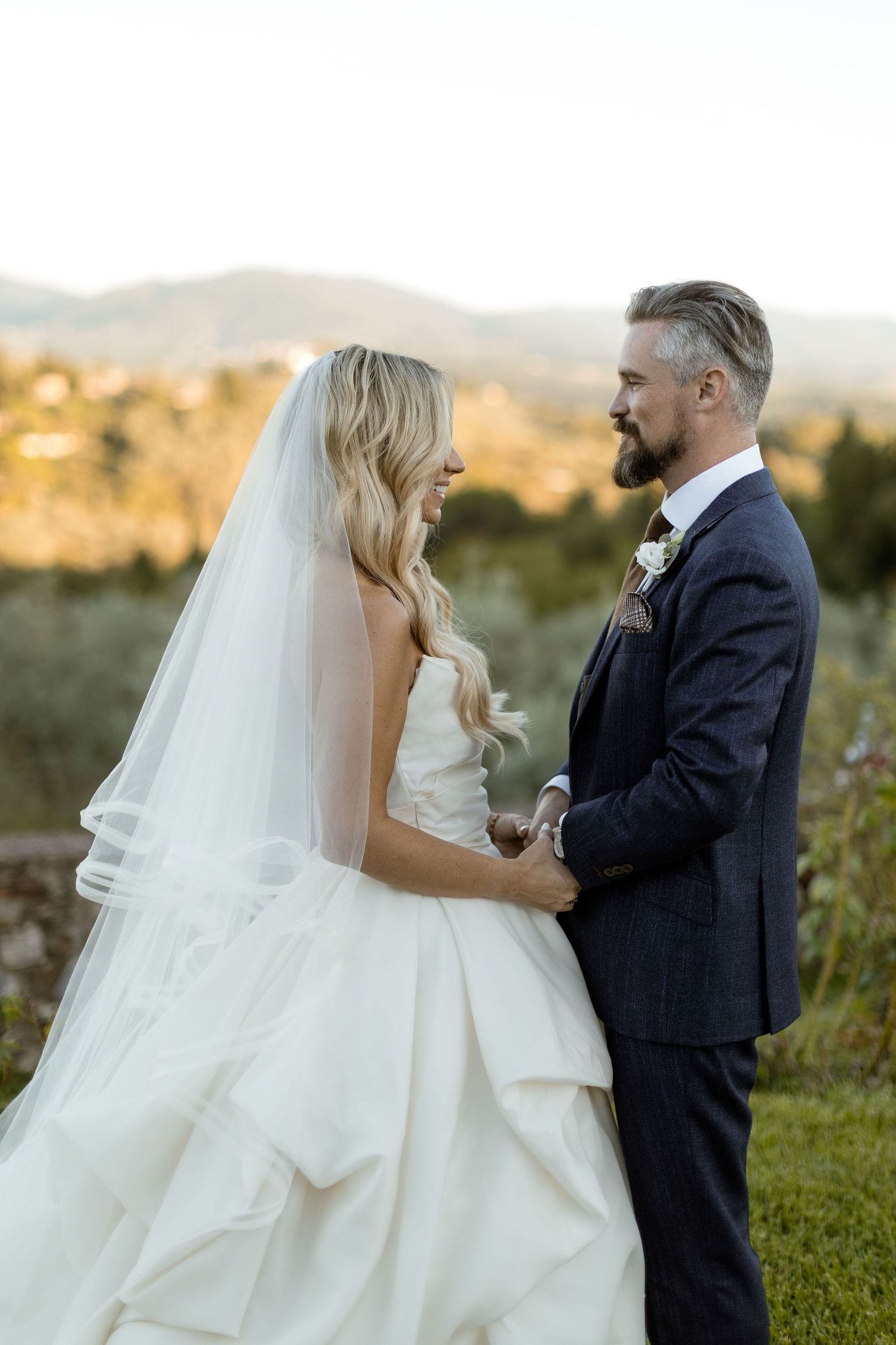 A couple shares an intimate moment at sunset in their wedding attire against a golden outdoor backdrop.