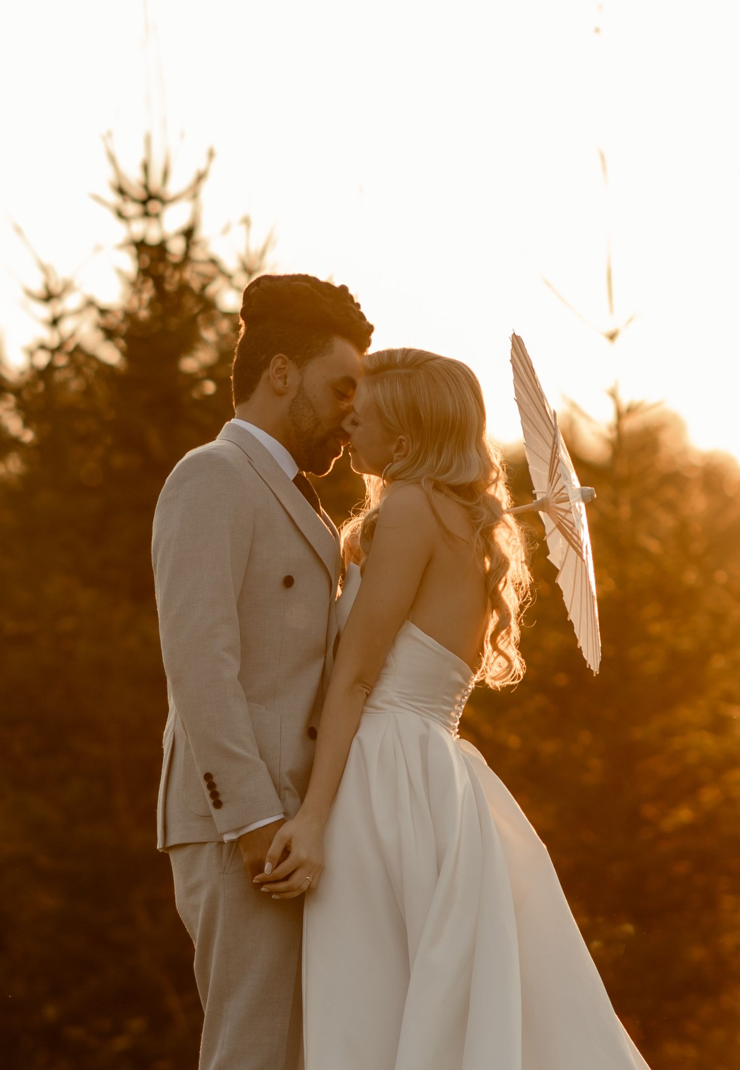 A romantic golden hour silhouette of a bride and groom sharing a tender moment during their sunset wedding photoshoot.