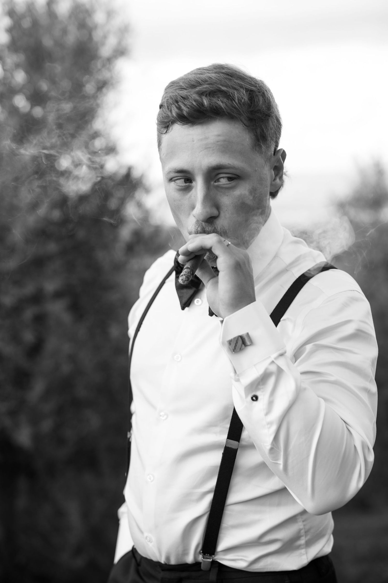 Black and white photo series showing a person in white shirt and suspenders smoking a cigarette in four sequential shots.