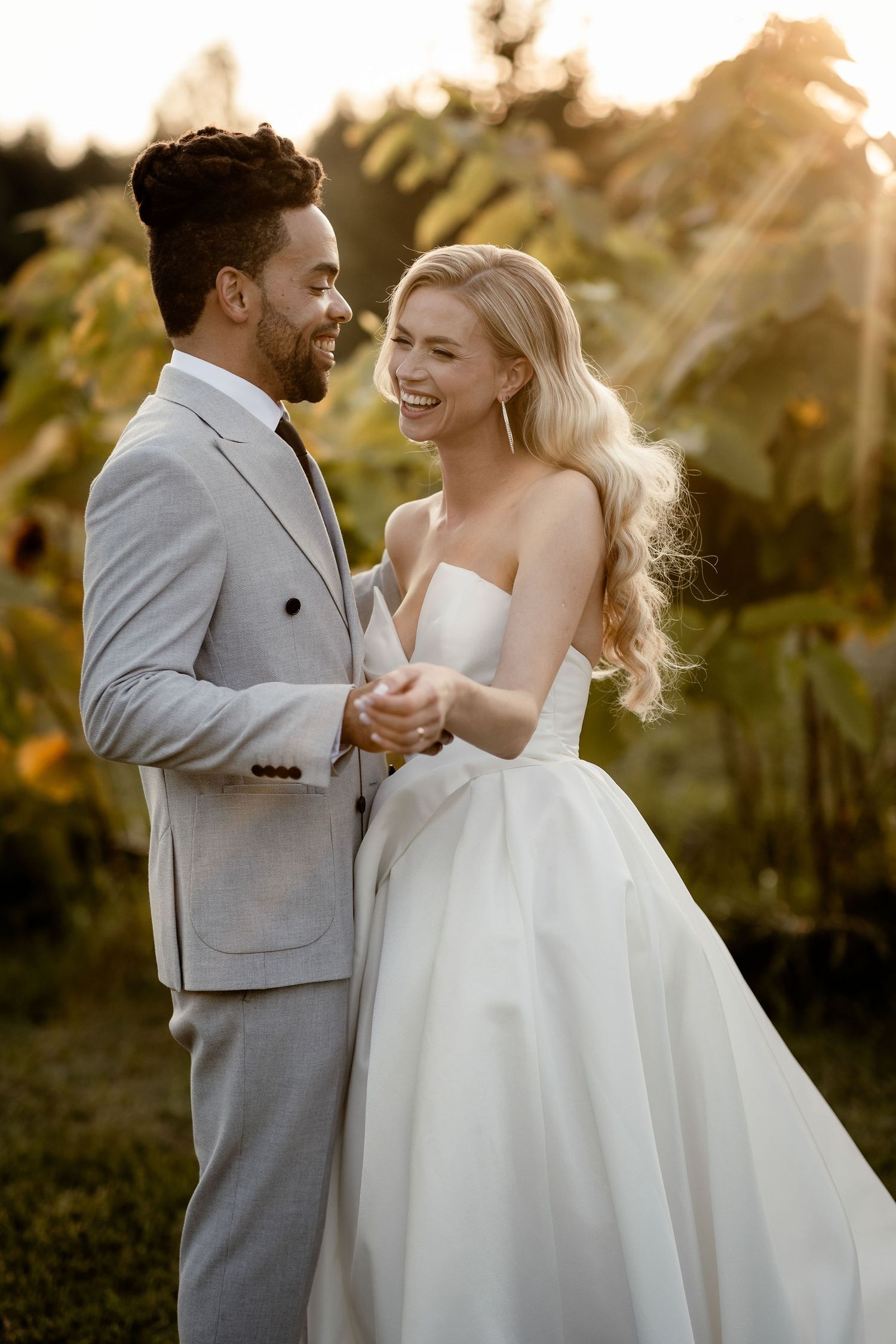 Intimate moment between newlyweds laughing together in warm sunset light.