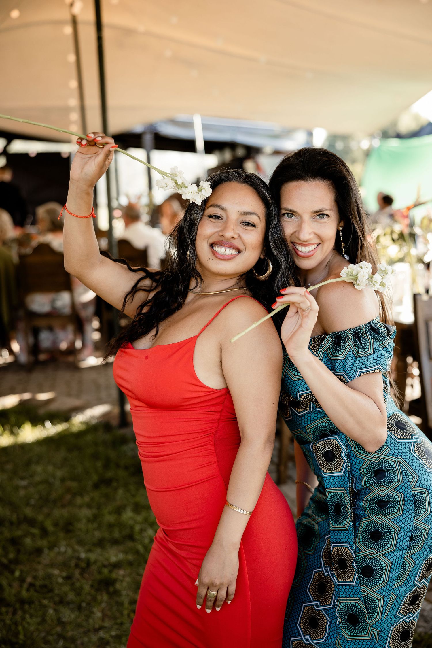 Two guests dancing and celebrating at an outdoor wedding reception under a tent.