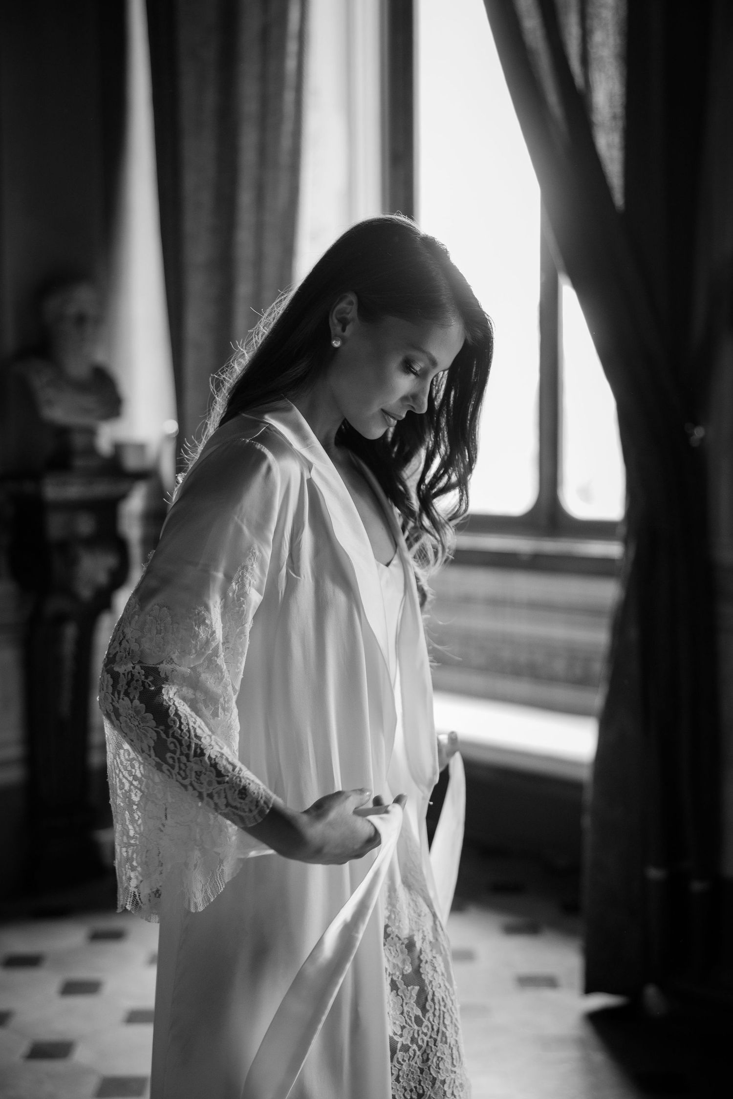A delicate white lace dress is captured in moody black and white photos showing elegant details and flowing fabric.