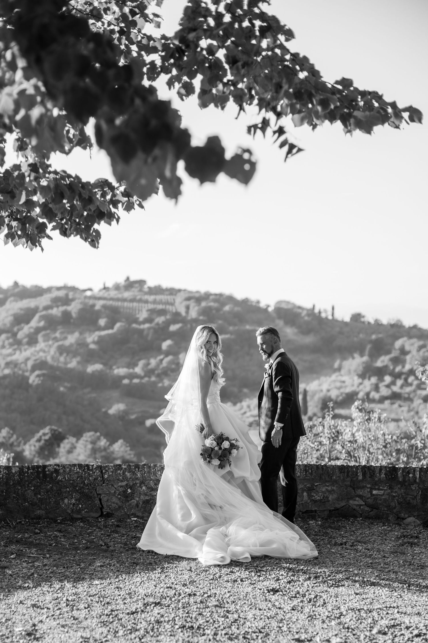 A romantic black and white wedding photoshoot sequence on a hilltop with flowing veil and natural scenery in the background.