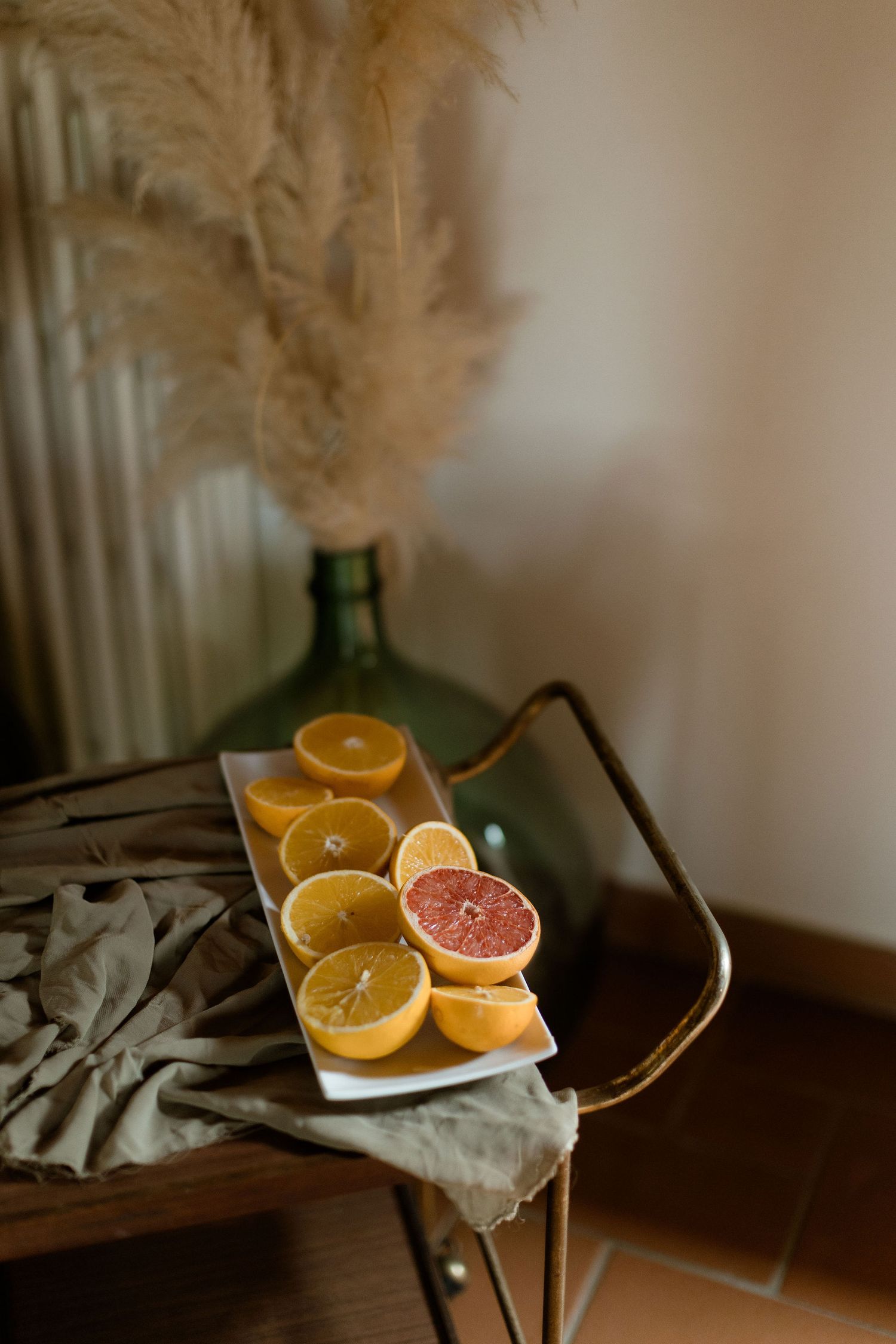 Sliced citrus fruits including oranges and grapefruit arranged on white plates against a moody dark background.