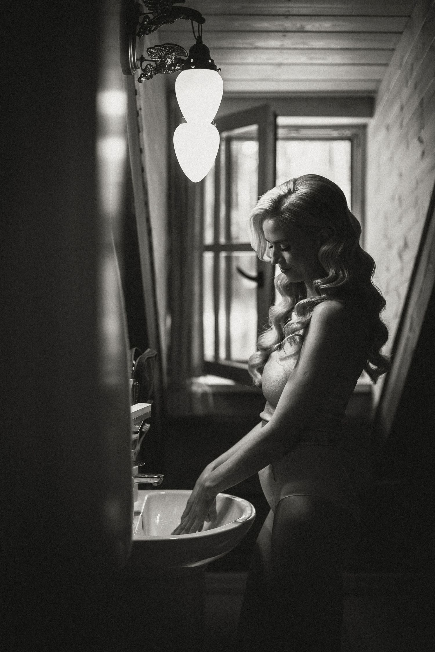 Black and white bridal preparation photo with vintage lighting fixtures.