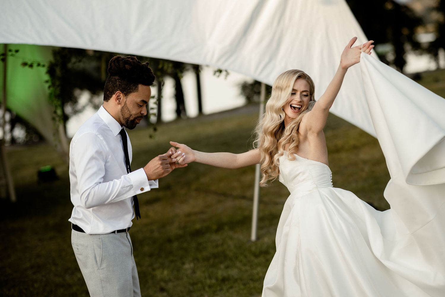A couple shares a playful dance moment at their outdoor wedding celebration.