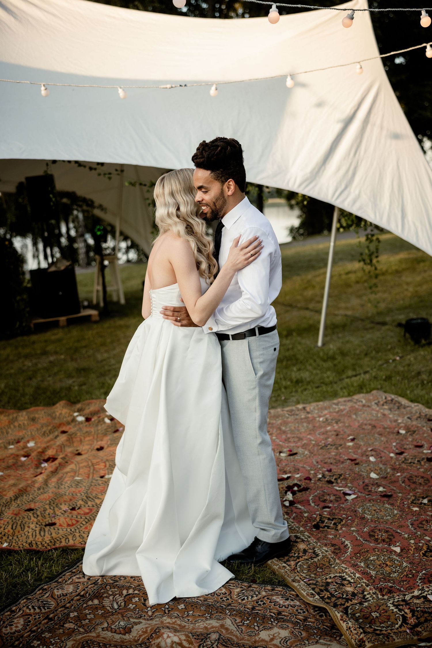 Intimate moment between couple under white tent at outdoor wedding.