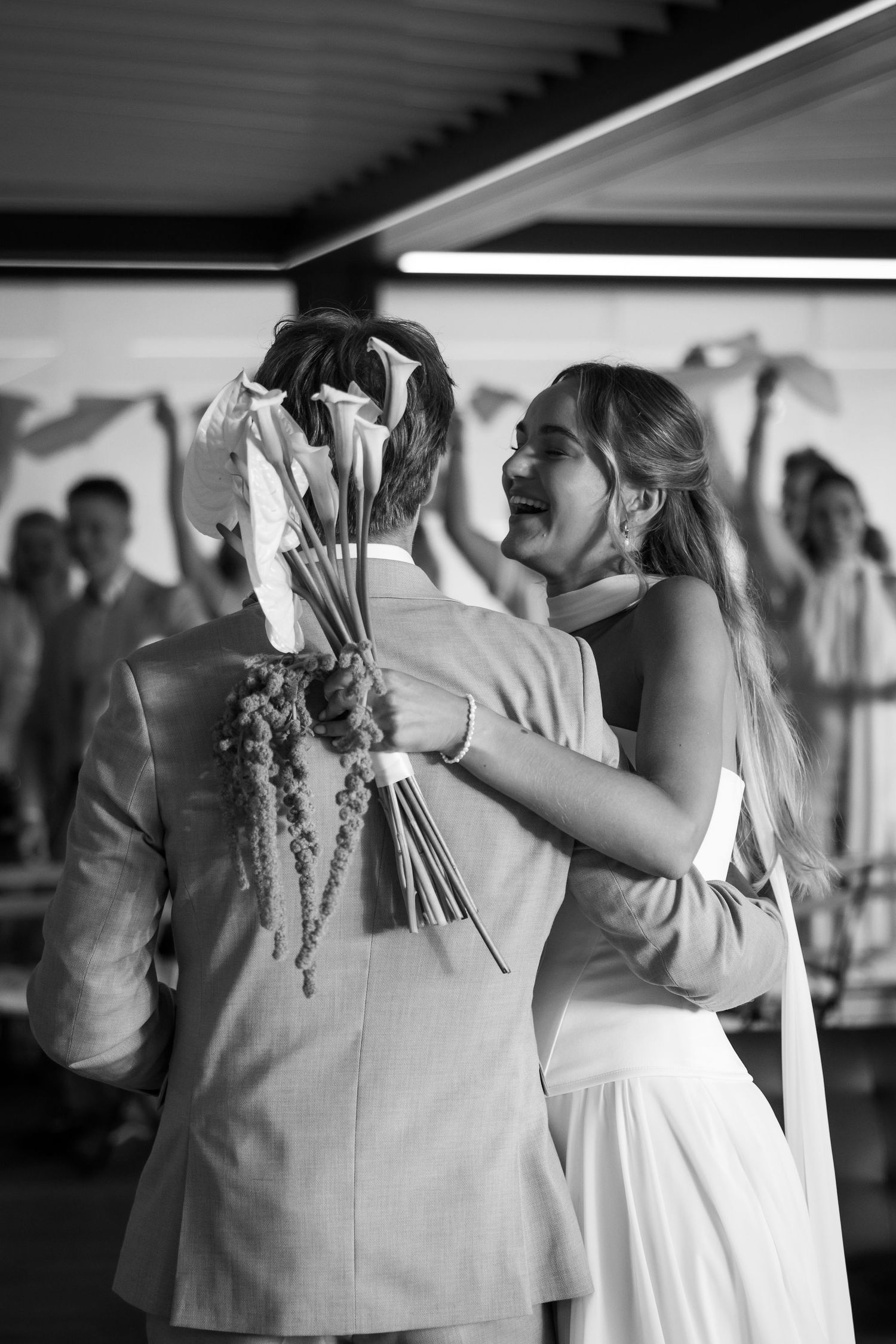 A joyful black and white photograph of a couple sharing their first dance at a wedding reception.