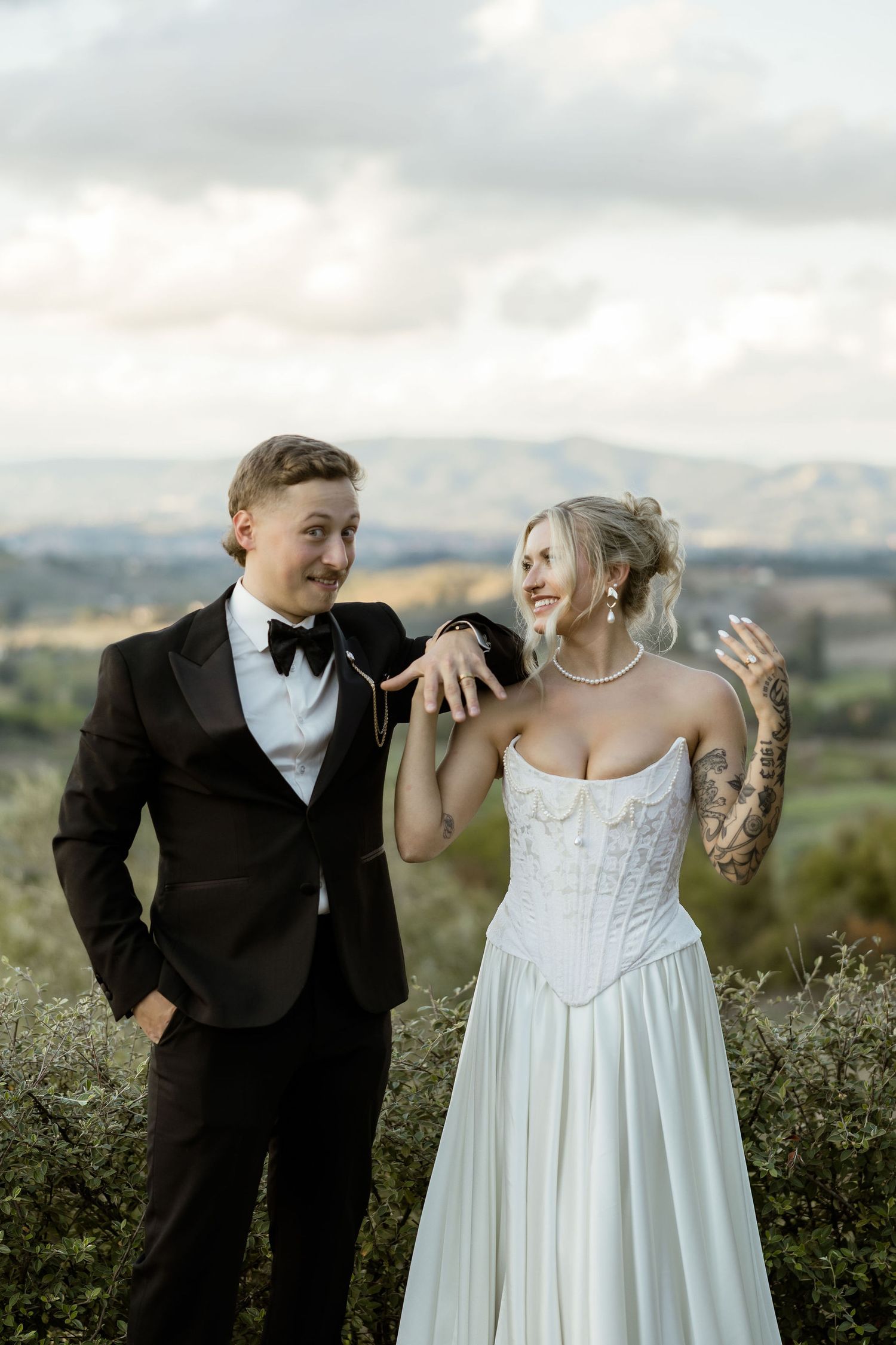 A bride and groom share joyful moments in a scenic mountain landscape with wildflowers.