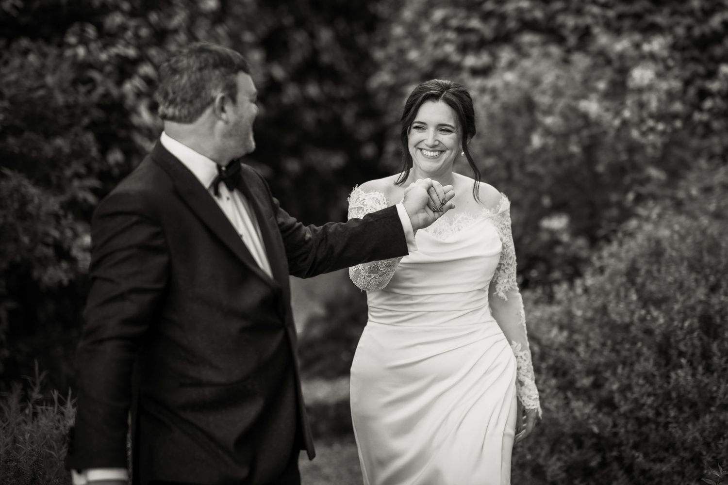 A romantic black and white photo of a couple at their wedding, showing an emotional moment in an outdoor setting.