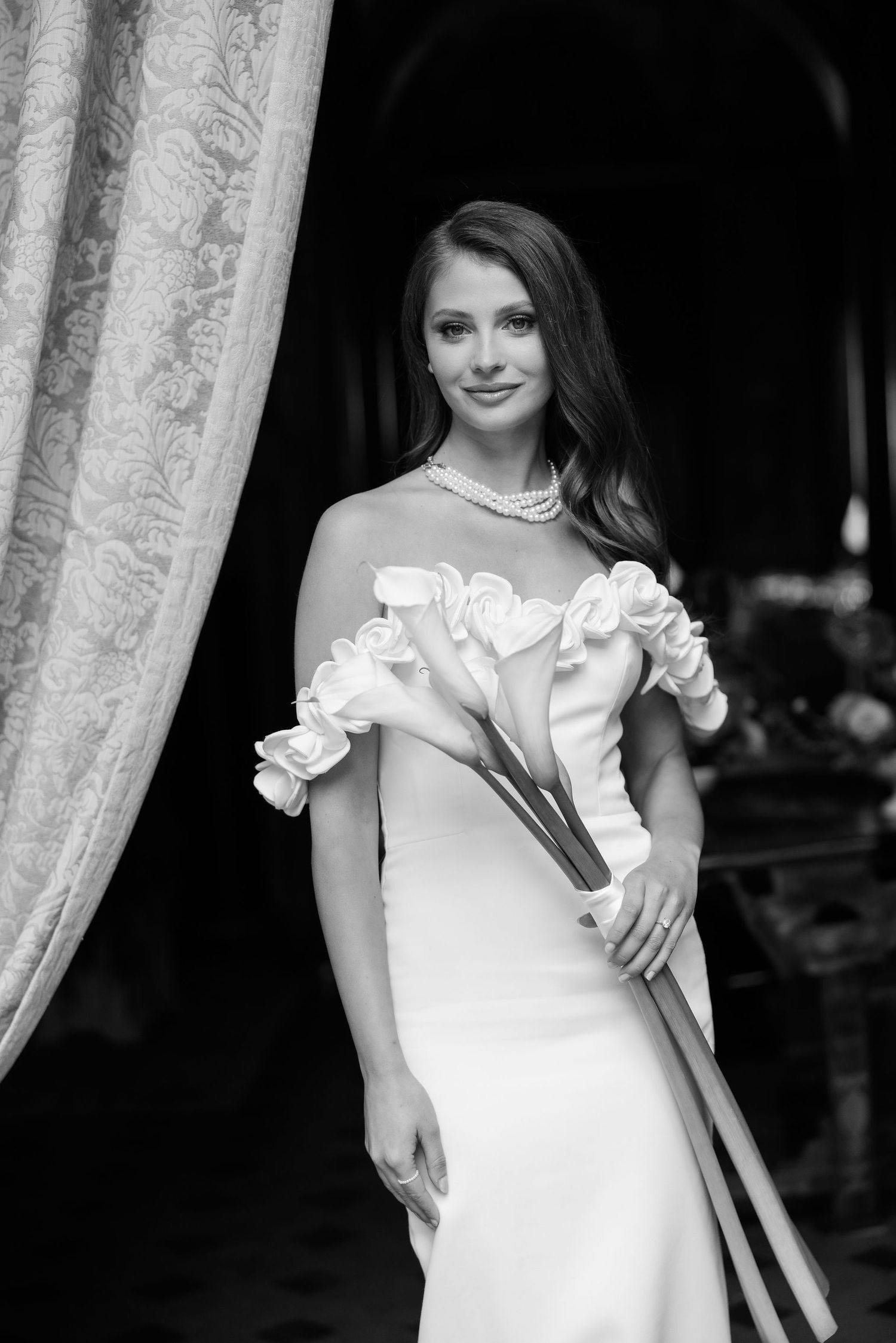 A series of classic black and white photos showing someone posing in an elegant white dress against a curtained backdrop.