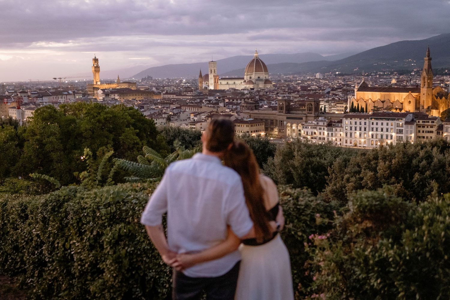 Couple enjoying scenic panoramic view of Florence's iconic skyline with Duomo cathedral at sunset.