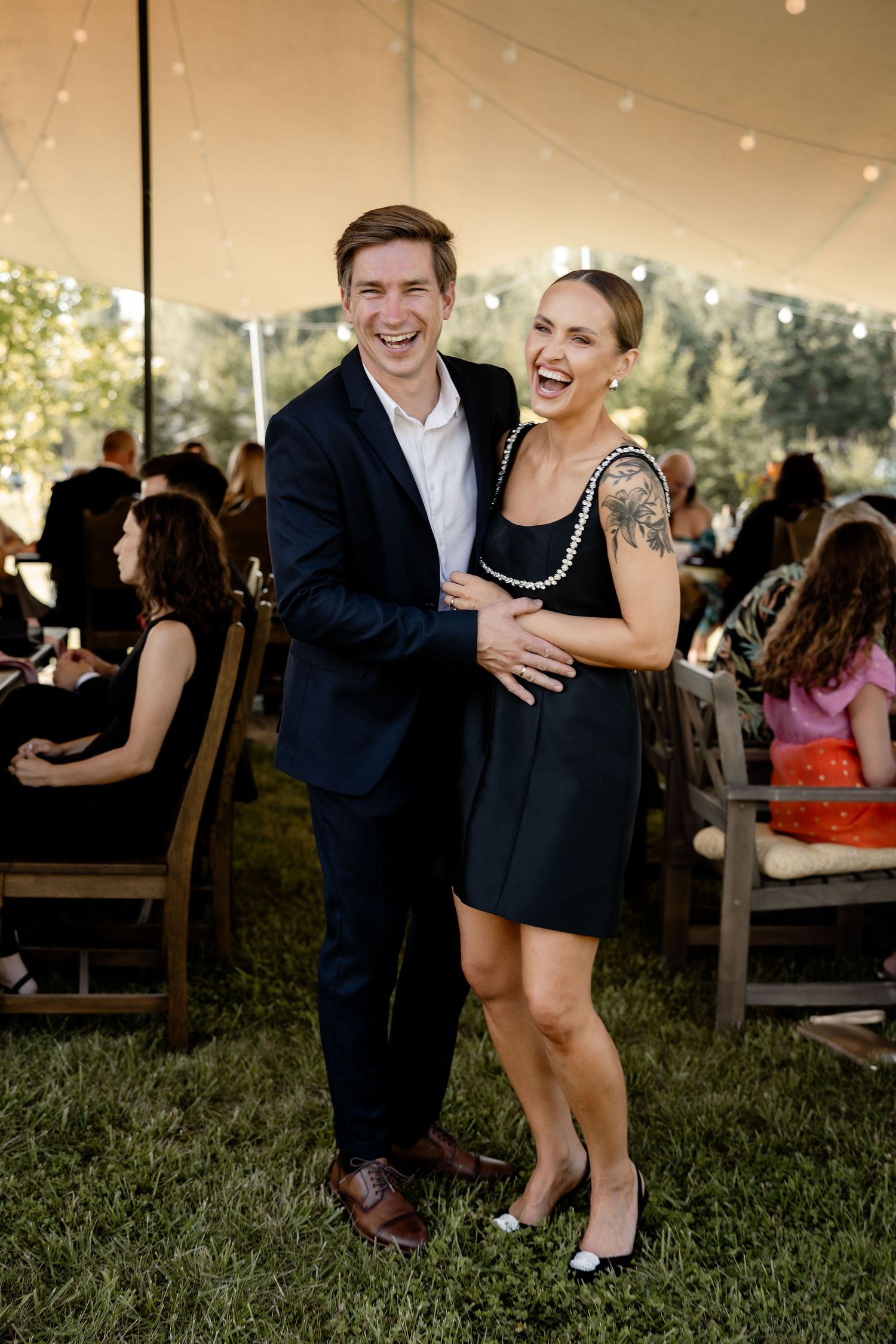 Couple enjoying themselves at an outdoor wedding reception under string lights.