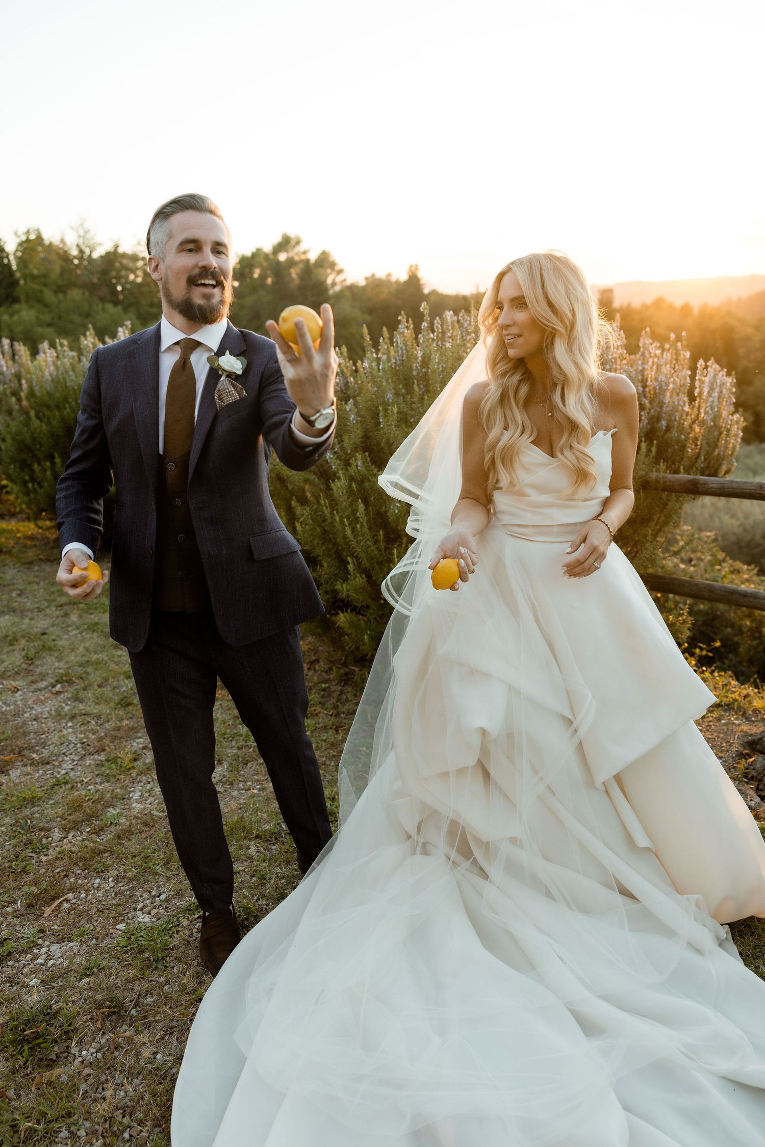 A wedding couple dances and twirls playfully in a natural outdoor setting during golden hour.