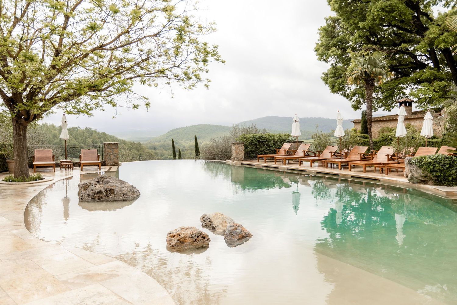 Luxury infinity pool with loungers overlooking scenic mountain views at an upscale resort property in nature.