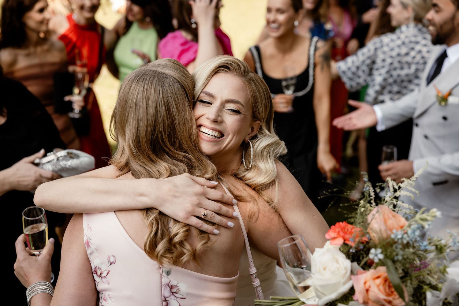 Emotional moment of hugging during wedding reception with flowers on table.