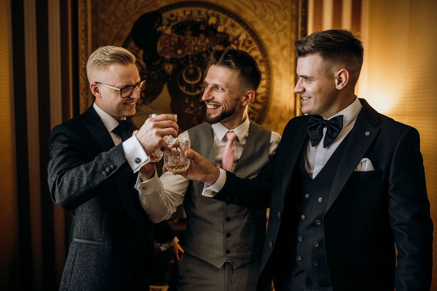 A group of people in formal attire laughing and socializing at an elegant indoor event.