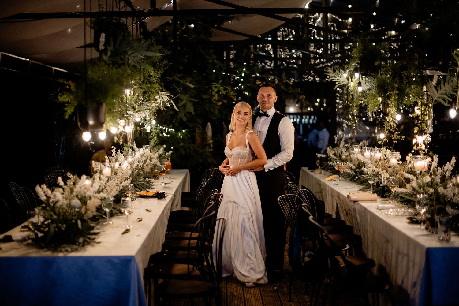 Romantic evening reception with elegantly decorated dining tables and hanging lights.