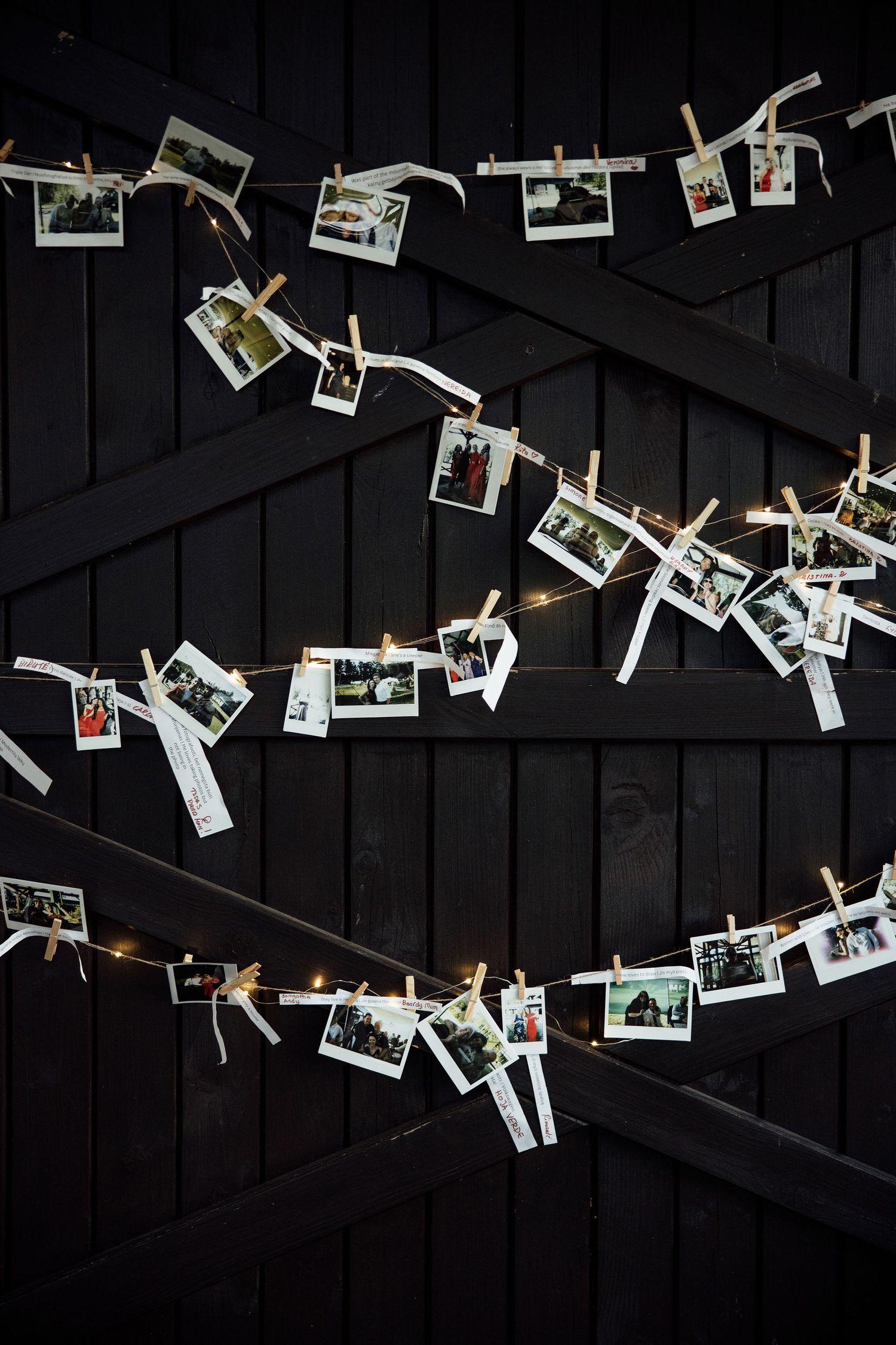 Polaroid instant photos hanging on string with wooden clothespins against a dark wooden wall background.