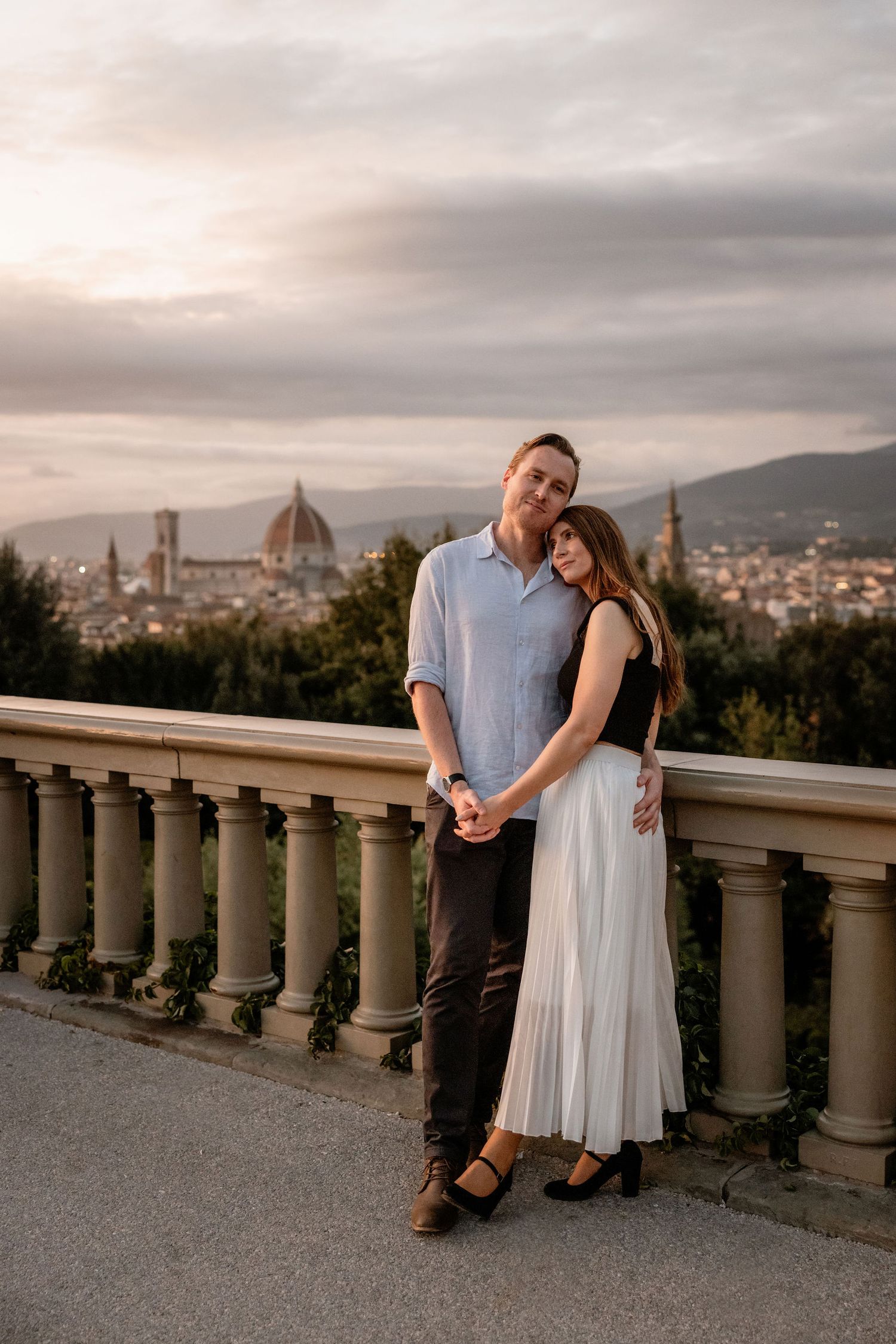 A couple embraces at sunset overlooking the iconic Florence skyline with the Duomo cathedral visible in the distance.