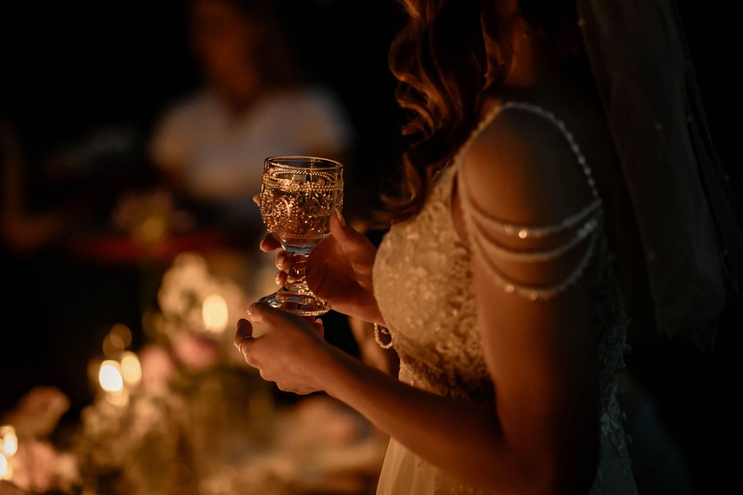 Candlelit wedding reception detail showing a glowing glass in evening light.