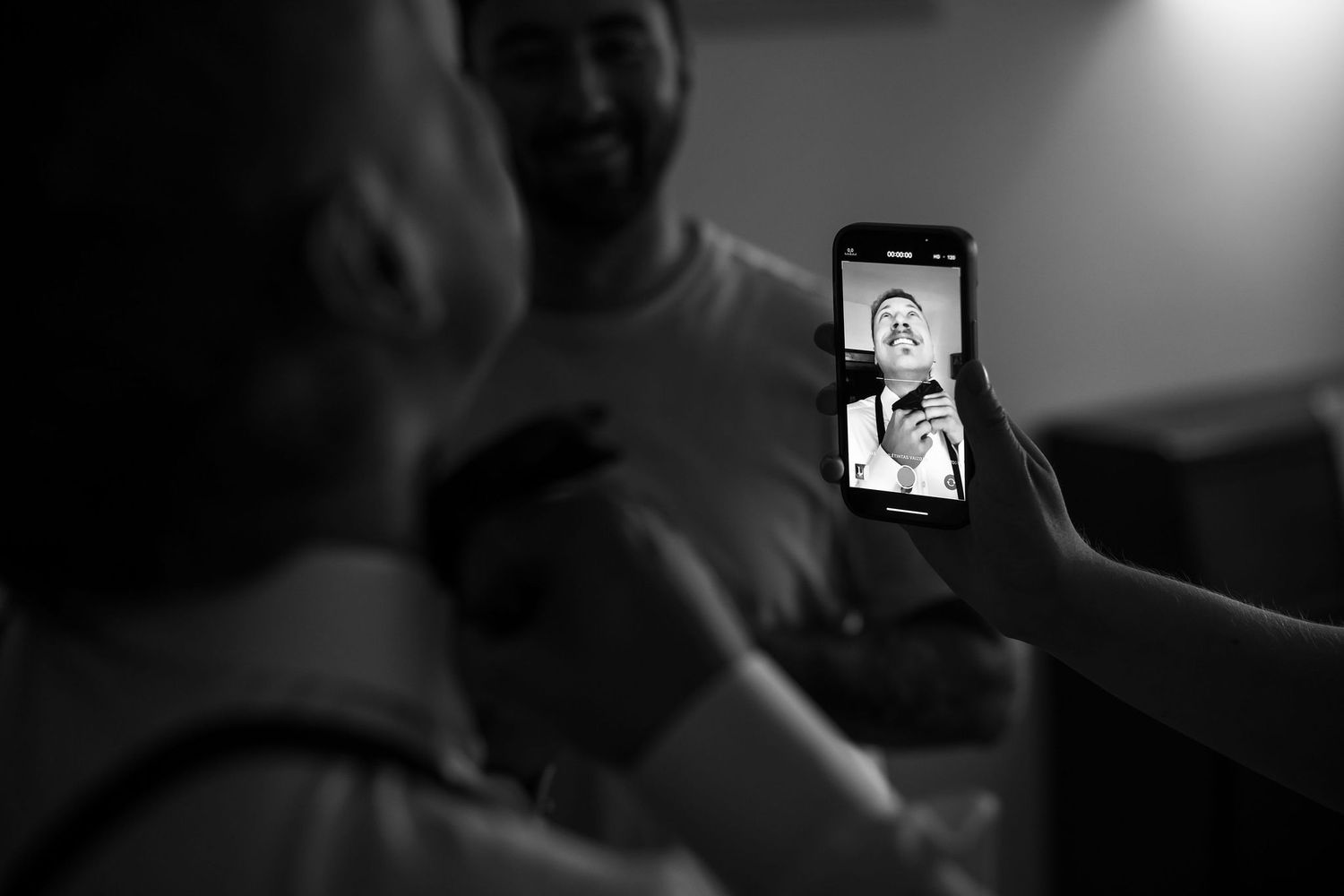 Seven black and white photos showing someone looking at a phone screen in a dark room.
