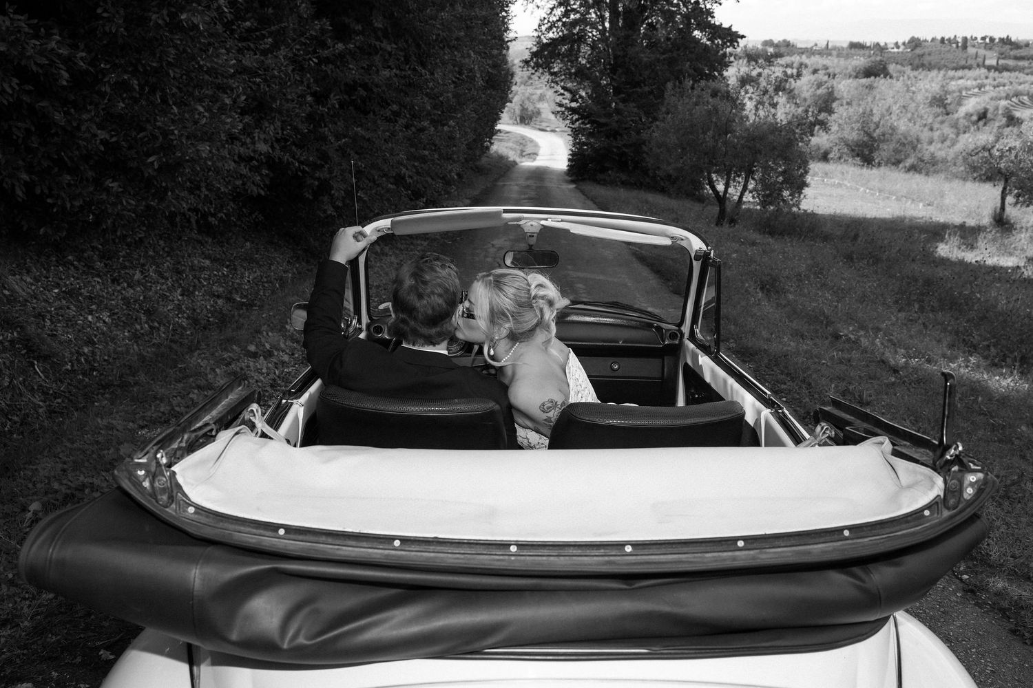 A sequence of black and white photos showing a convertible car with its roof folding down into the trunk compartment.