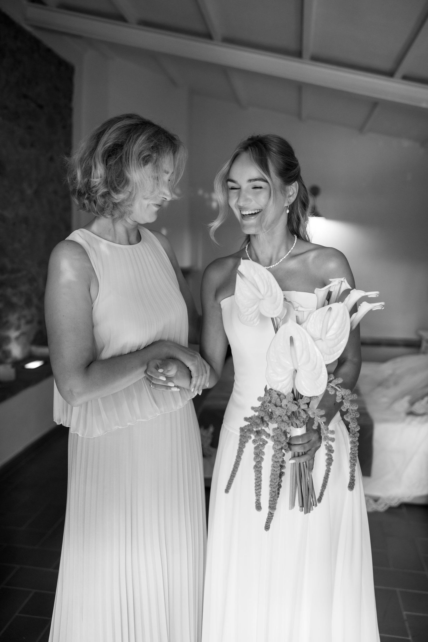 People in white dresses sharing joyful moments and embracing at an indoor celebration.