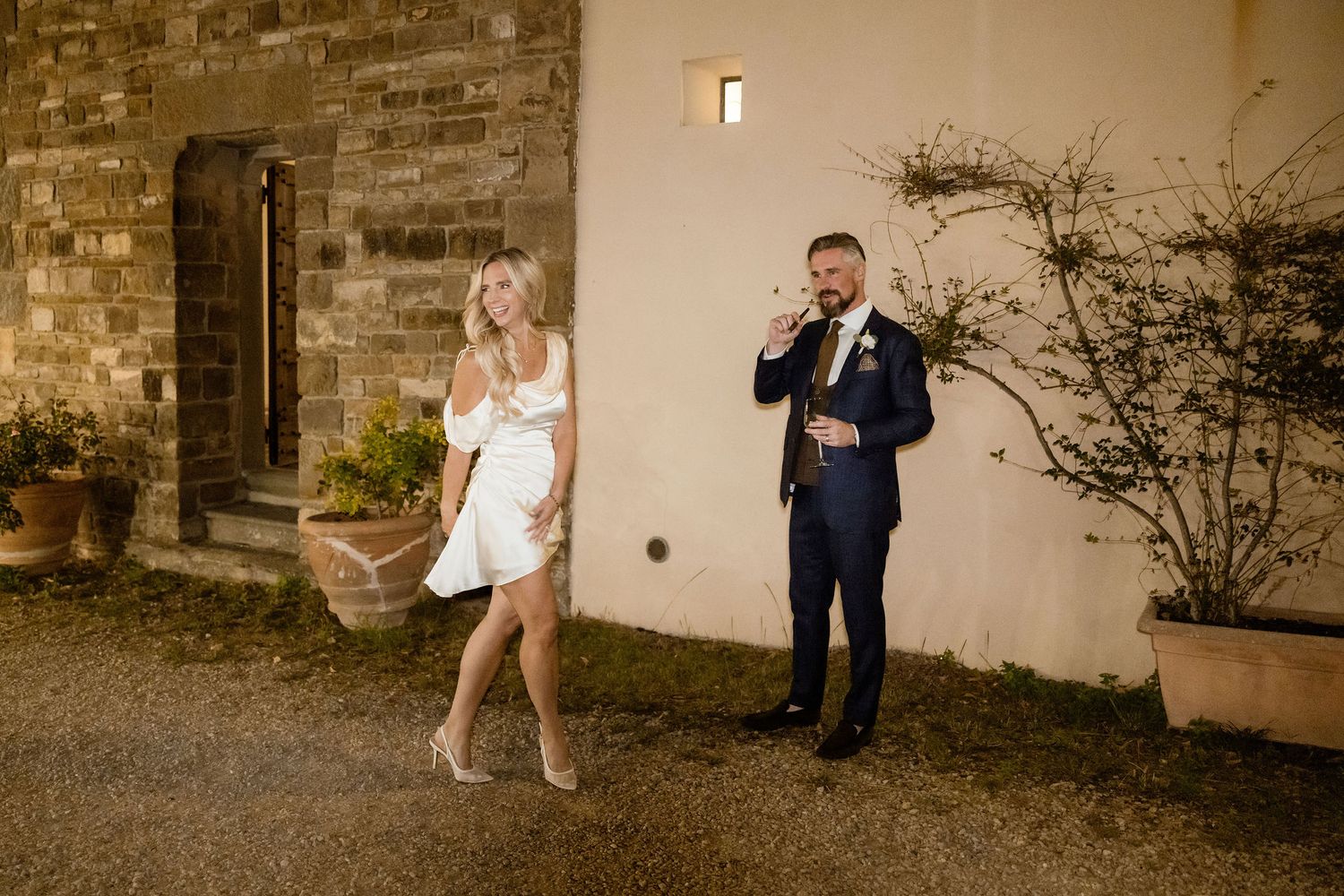 A couple shares a romantic moment against a rustic stone wall background during their wedding photo session.