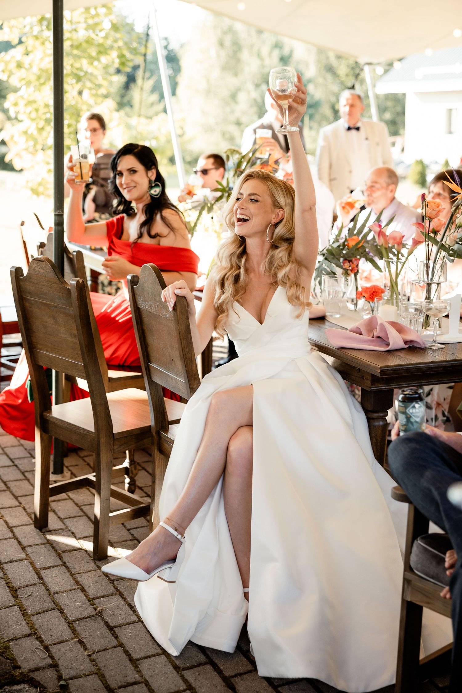 Wedding celebration under tent with guests raising glasses in a toast.