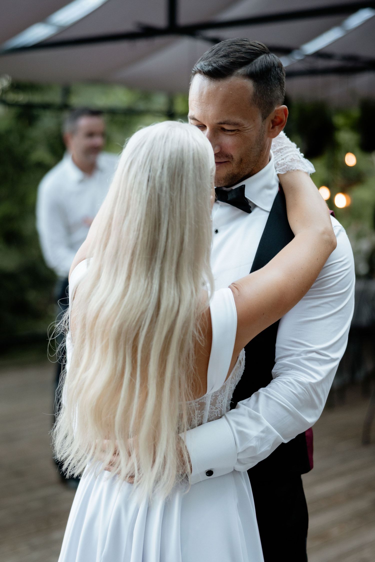 A bride in a white corset dress dances enthusiastically at an outdoor evening celebration.