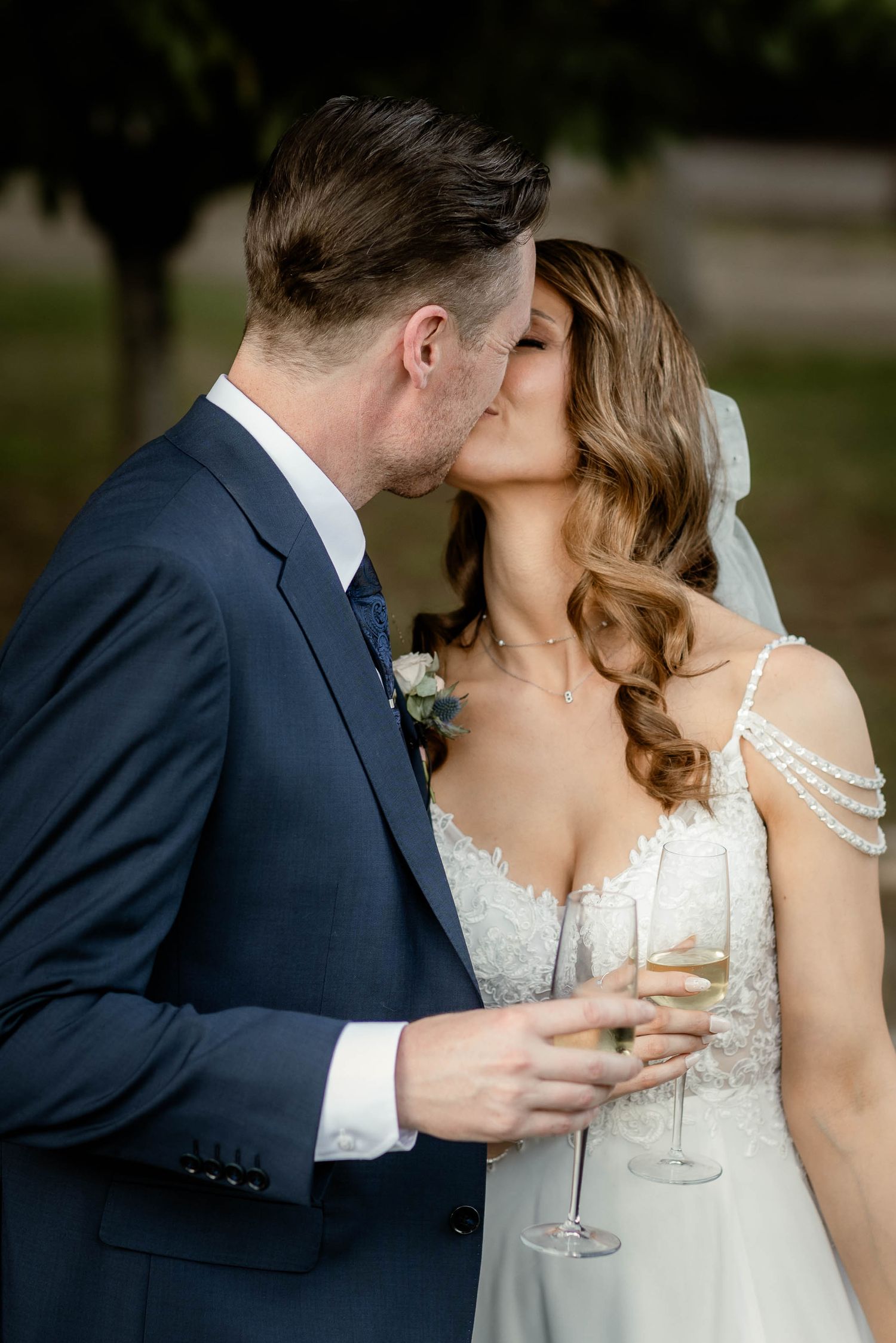 Romantic champagne toast and kiss between newlyweds in elegant wedding attire.