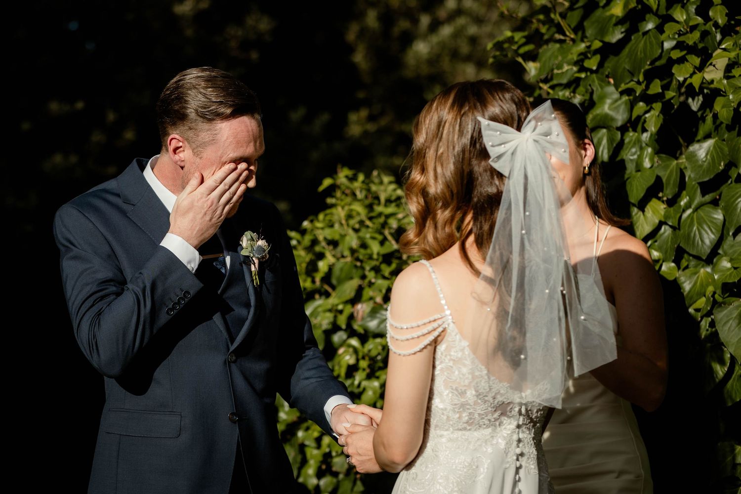 An emotional moment captured during an outdoor wedding ceremony among lush greenery.