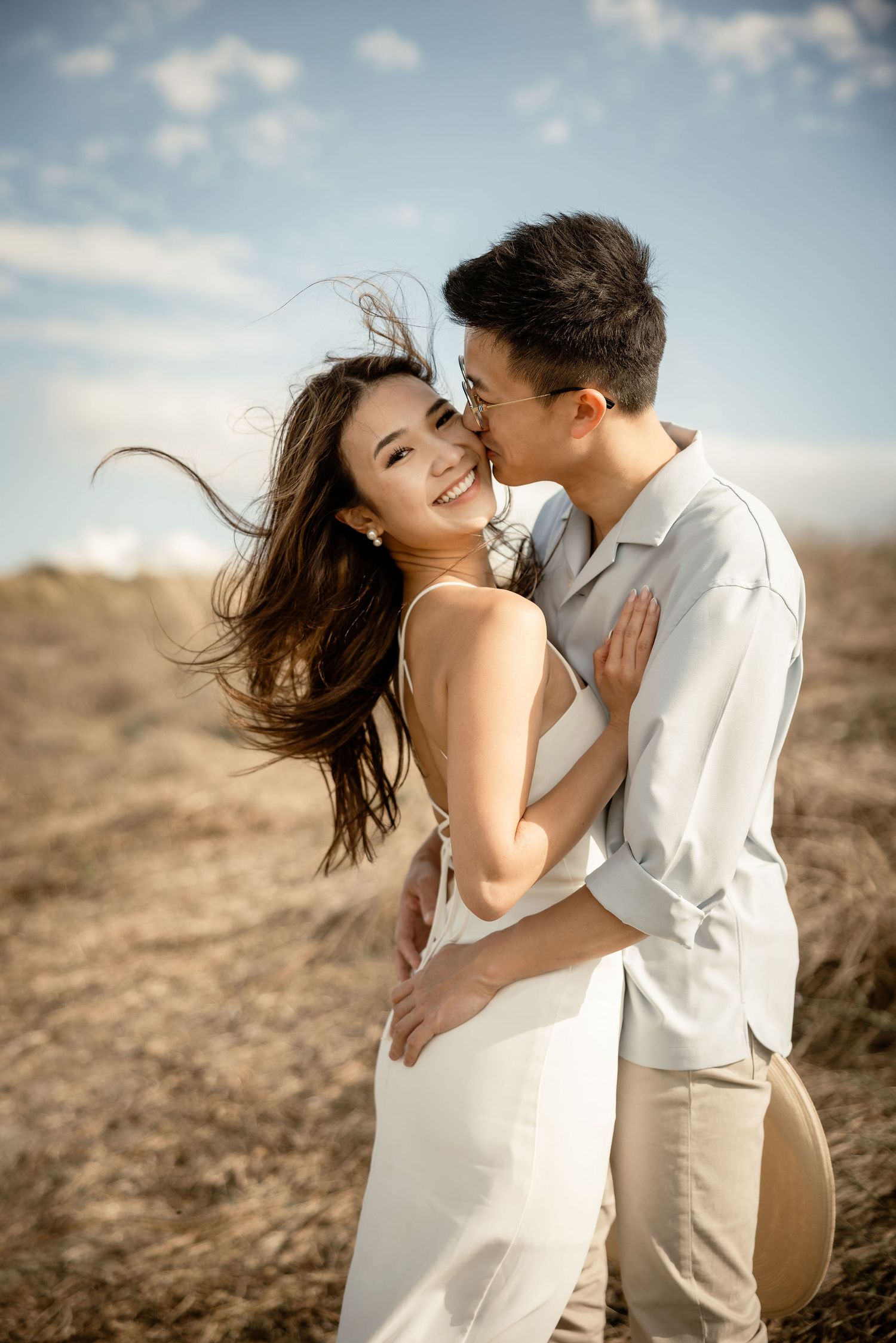 A candid moment of joy and laughter shared on a scenic hillside in summer outfits.