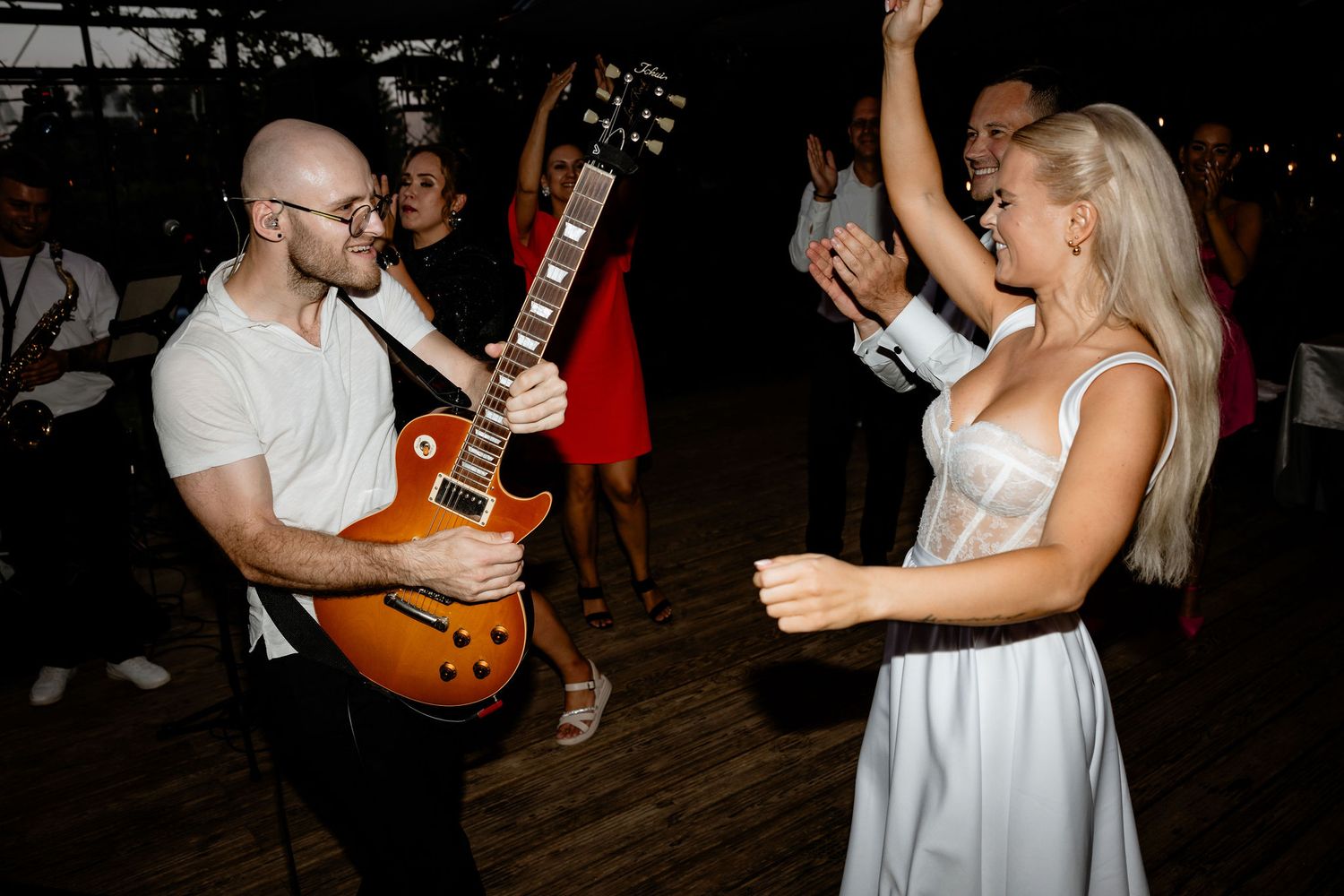 Wedding reception dance party with guitarist and dancing in white dress.