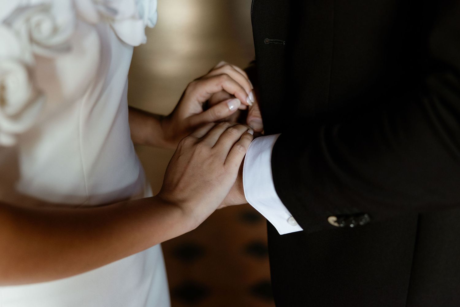 Close-up view of hands clasping together during an intimate wedding ceremony moment.