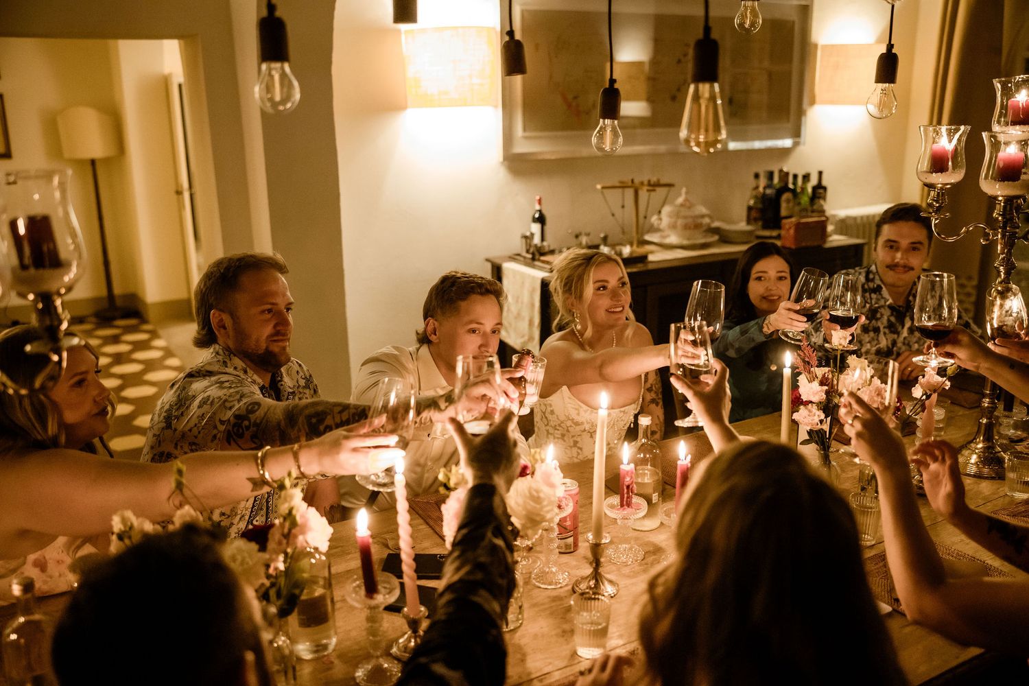 Warm candlelit dinner table setting with multiple guests enjoying an elegant evening meal.