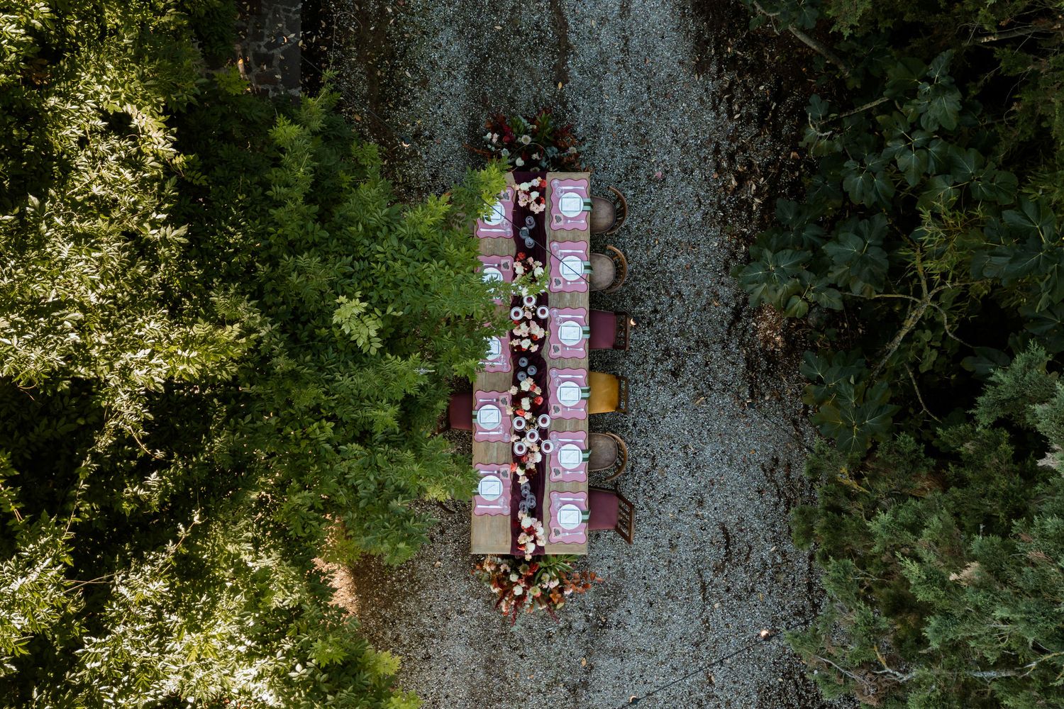 Drone shot of people walking along a stone pathway through dense green forest canopy.
