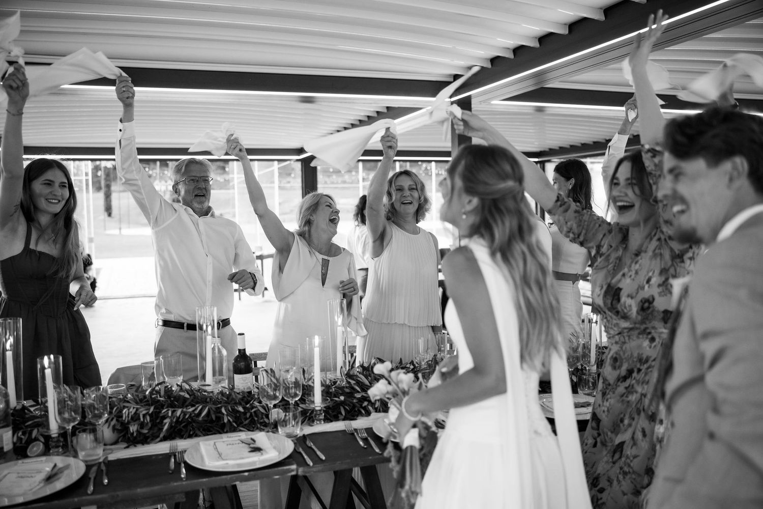 Black and white photo showing people gathered at a social event under a covered outdoor space.
