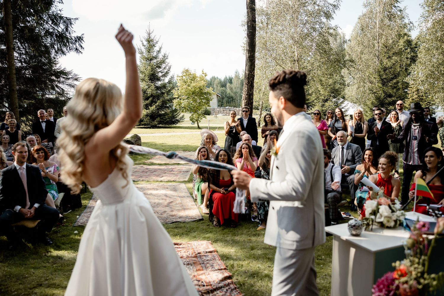An outdoor wedding celebration with guests watching as couple shares a celebratory moment.