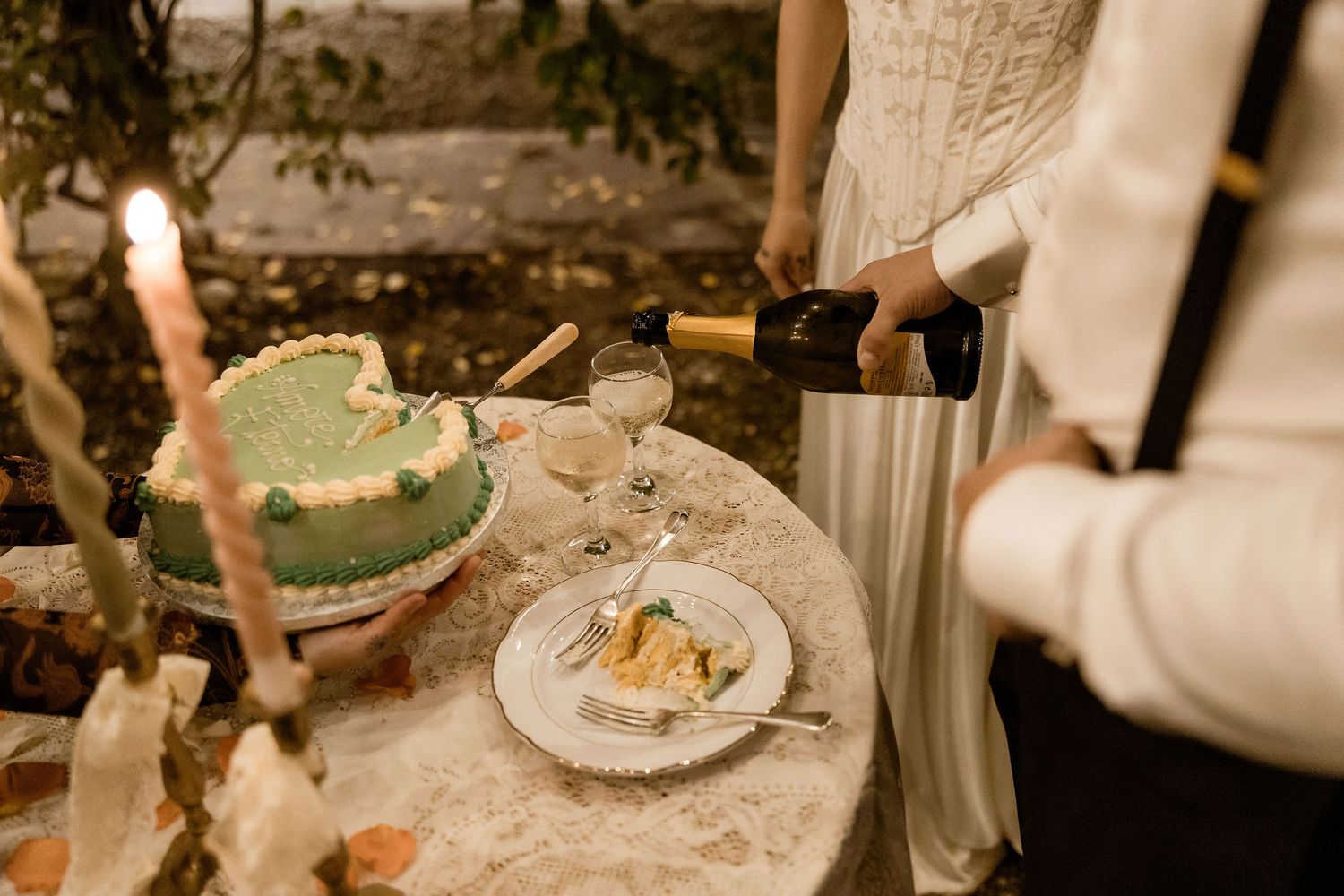 Cozy outdoor table setting with a green ceramic bowl, white plate, and someone pouring from a stainless steel container.