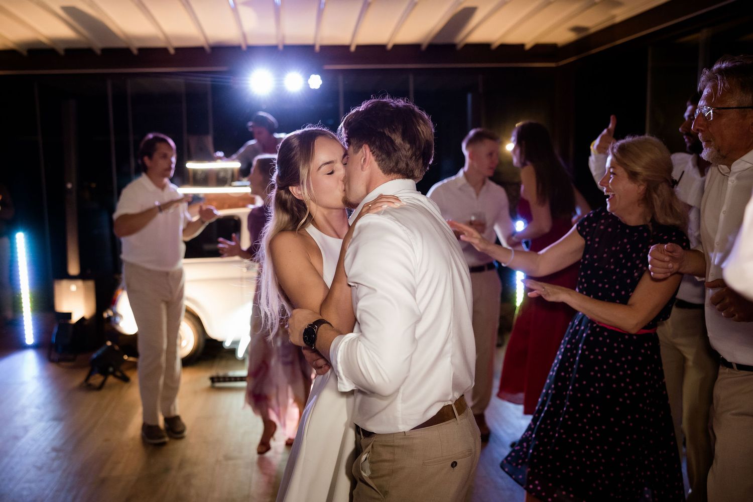 Couples slow dancing together at an evening wedding reception with dramatic lighting and shadows.