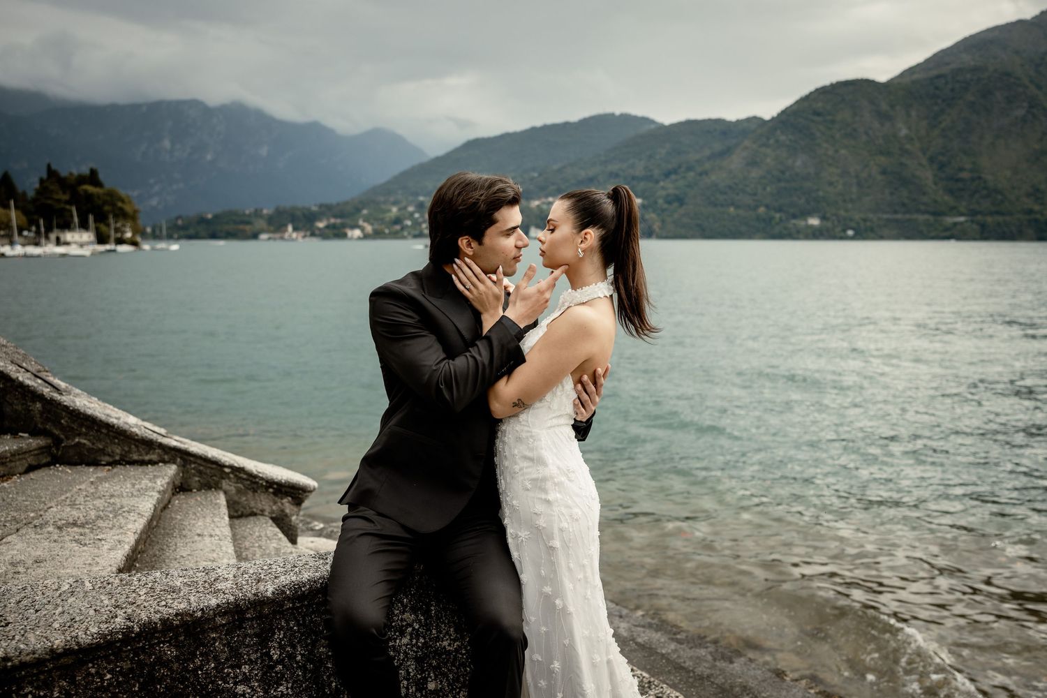 Newlyweds embrace by scenic mountain lake during romantic wedding photoshoot.