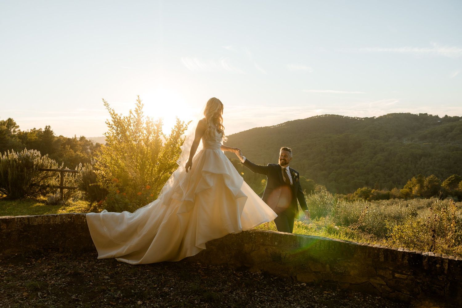 Newlywed couple walking together at sunset in a scenic mountain landscape with flowing white wedding dress.